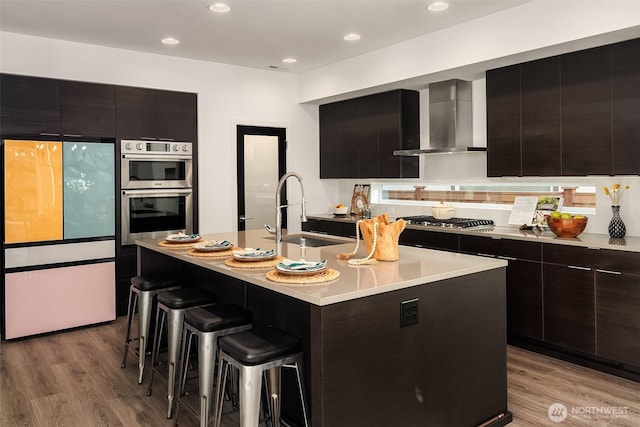 16515 26th St E, Lake Tapps, WA 98391 - kitchen featuring appliances with stainless steel finishes, a sink, wall chimney range hood, a breakfast bar, and modern cabinets