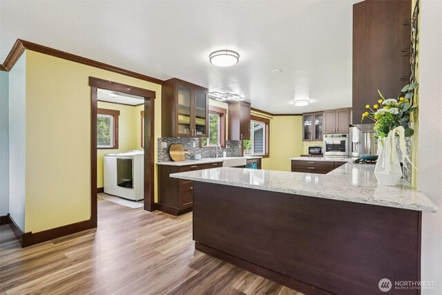 3718 NE Everett St, Camas, WA 98607 - kitchen with washer / dryer, appliances with stainless steel finishes, decorative backsplash, glass insert cabinets, and light wood-style flooring