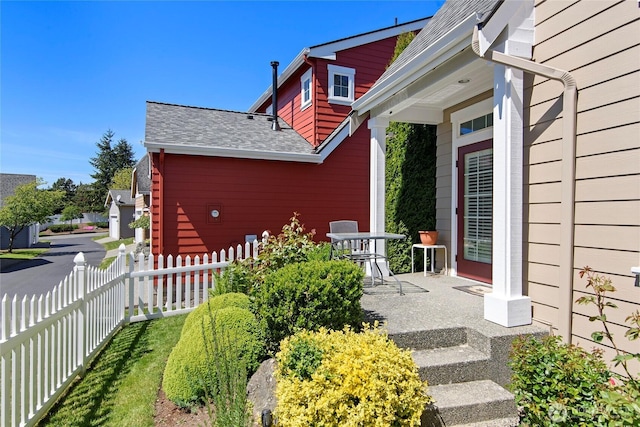 view of property exterior with fence and a shingled roof