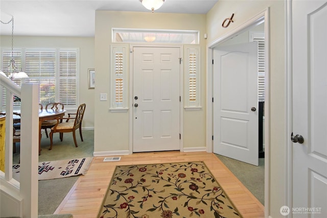 foyer entrance with light wood-style floors, a chandelier, and baseboards