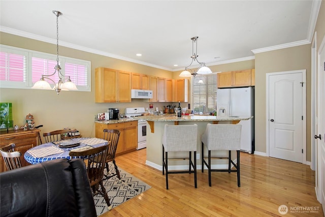 kitchen with white appliances, light brown cabinetry, a breakfast bar area, crown molding, and light wood-style floors