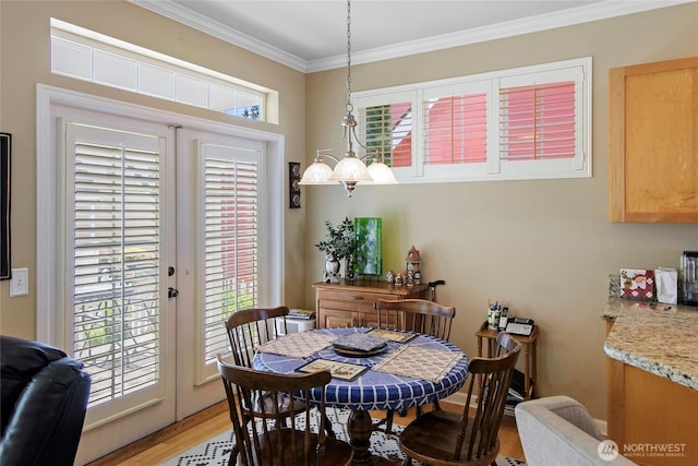 dining space with crown molding, light wood-type flooring, healthy amount of natural light, and french doors