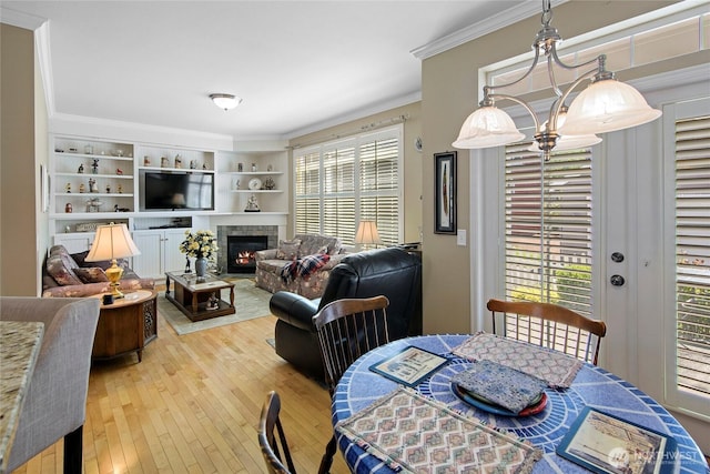 dining area featuring crown molding, hardwood / wood-style flooring, and a glass covered fireplace