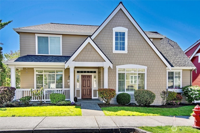 view of front of home featuring a shingled roof, a porch, and a front yard