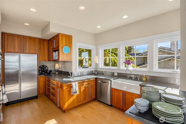 10915NE S Beach Rd, Bainbridge Island, WA 98110 - kitchen featuring appliances with stainless steel finishes, a sink, brown cabinetry, light wood-style floors, and recessed lighting