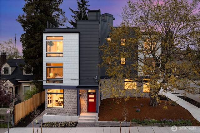 view of front of house featuring brick siding and fence