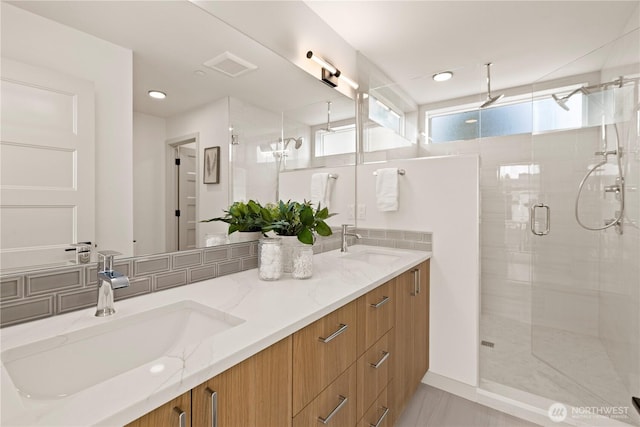 full bathroom with a shower stall, double vanity, visible vents, and a sink