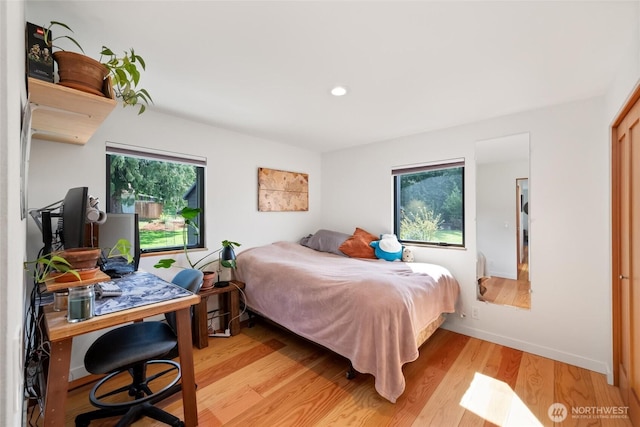 bedroom with light wood finished floors, baseboards, multiple windows, and recessed lighting
