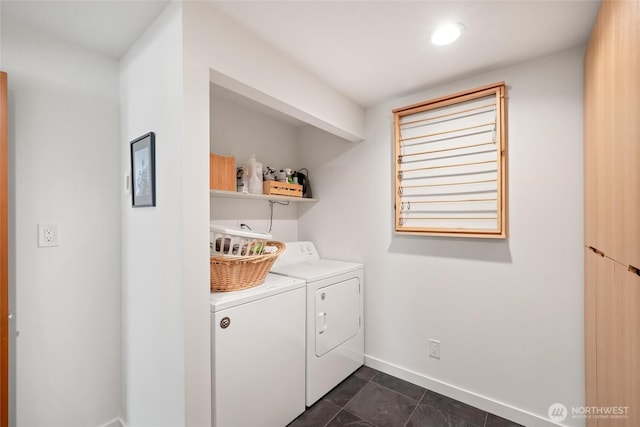 clothes washing area featuring dark tile patterned floors, separate washer and dryer, laundry area, and baseboards