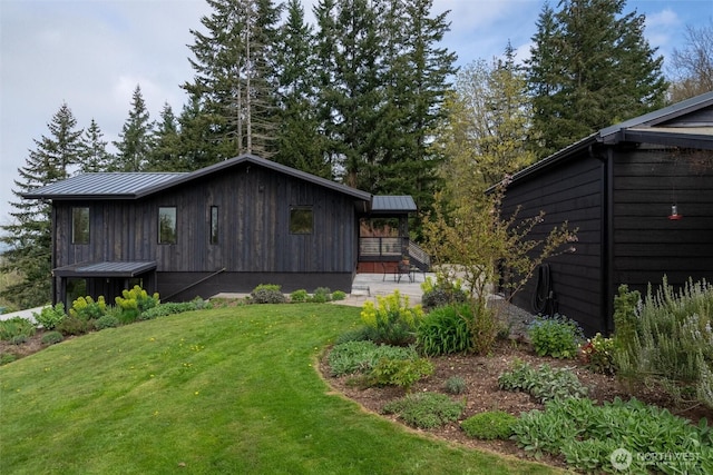 exterior space featuring metal roof, a standing seam roof, and a lawn