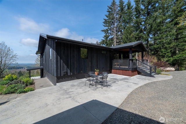 back of property featuring metal roof, outdoor dining space, and a patio