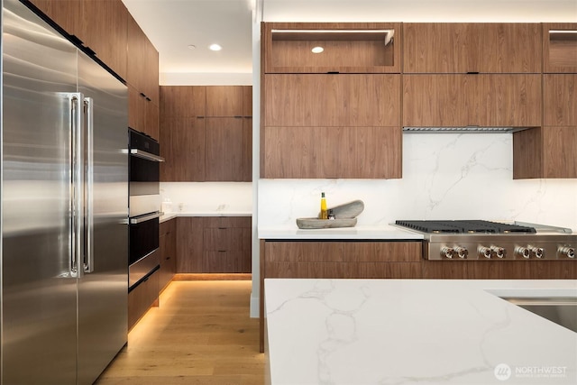 11896 SE 5th St, Bellevue, WA 98805 - kitchen featuring decorative backsplash, modern cabinets, light stone countertops, light wood finished floors, and stainless steel appliances