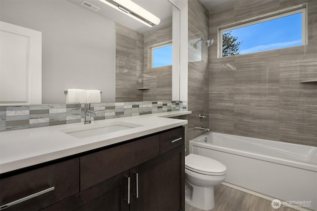 bathroom featuring vanity, shower / tub combination, toilet, visible vents, and decorative backsplash