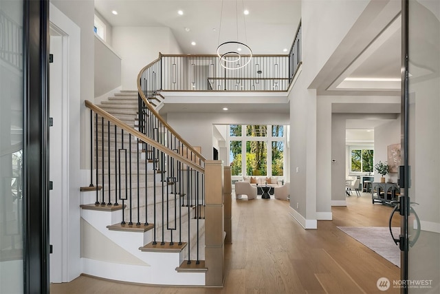 foyer entrance with baseboards, a notable chandelier, recessed lighting, wood finished floors, and stairs