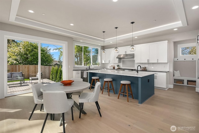 dining room featuring recessed lighting, light wood-style flooring, and a tray ceiling