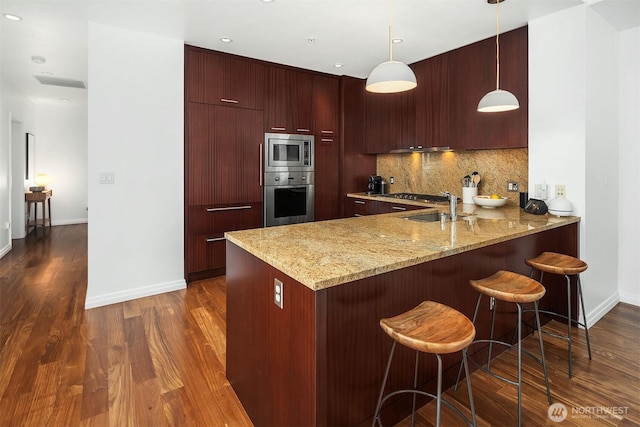 kitchen featuring baseboards, a peninsula, dark wood-type flooring, modern cabinets, and appliances with stainless steel finishes