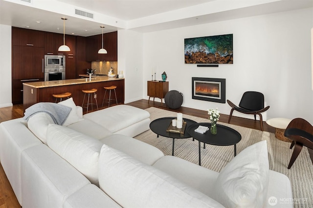 living area featuring dark wood-type flooring, visible vents, and baseboards