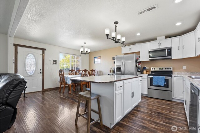 804 S Adams Ave, Warden, WA 98857 - kitchen with white cabinets, a notable chandelier, visible vents, and appliances with stainless steel finishes
