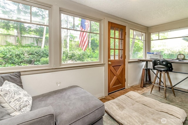 sunroom featuring a textured ceiling, a healthy amount of sunlight, and wood finished floors