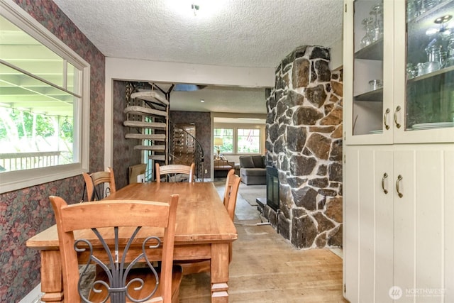 dining area with wallpapered walls, a textured ceiling, and wood finished floors