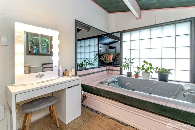 bathroom featuring a tub with jets and beam ceiling