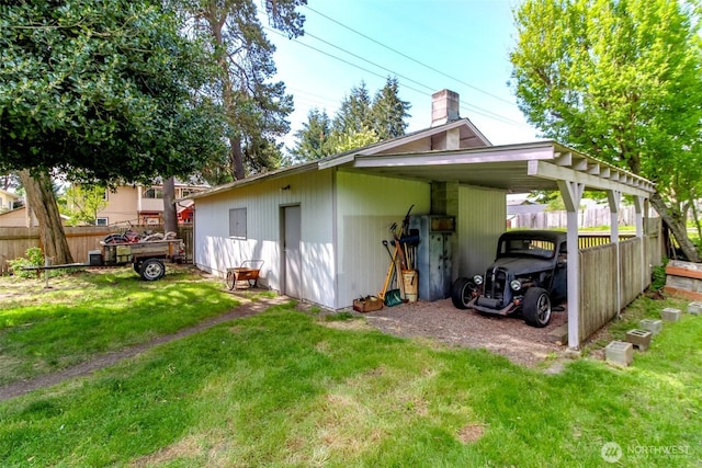 back of property with fence, a carport, and a lawn