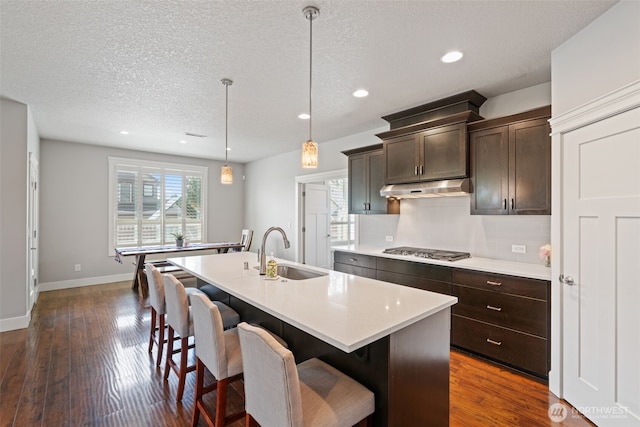 4407 N Ridgefield Woods Dr, Ridgefield, WA 98642 - kitchen with a sink, under cabinet range hood, stainless steel gas stovetop, light countertops, and dark brown cabinets