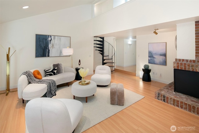 living area featuring stairway, wood finished floors, baseboards, recessed lighting, and a towering ceiling