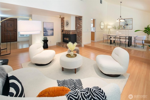 living area with wood finished floors, healthy amount of natural light, a chandelier, and a fireplace