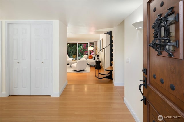 entryway featuring stairway, light wood-style floors, and baseboards
