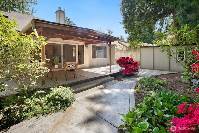 back of house with fence, a chimney, a deck, and a patio area