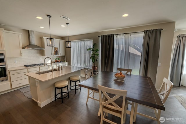 29027 NE 156th St, Duvall, WA 98019 - kitchen with visible vents, a sink, wall chimney range hood, an island with sink, and decorative backsplash