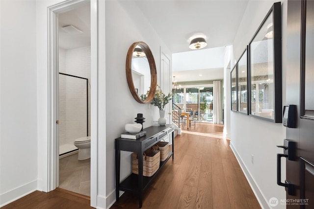 hall with a chandelier, wood-type flooring, and baseboards