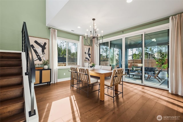 dining space with recessed lighting, hardwood / wood-style floors, an inviting chandelier, and stairs