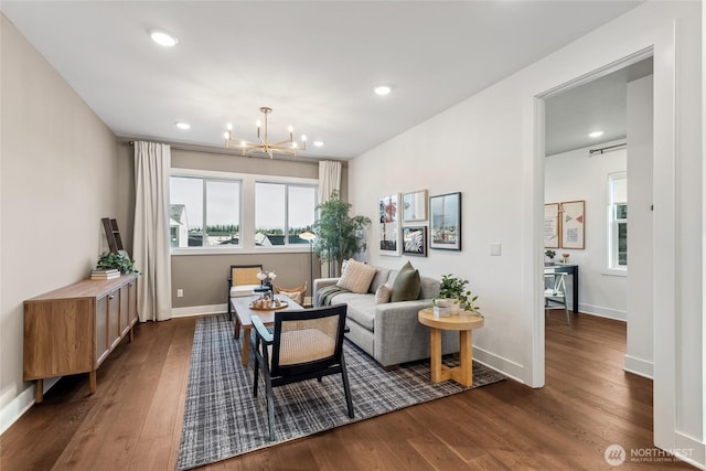 living area featuring dark wood-type flooring, a healthy amount of sunlight, and a notable chandelier