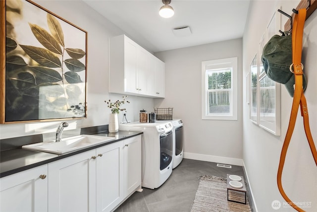 clothes washing area with separate washer and dryer, baseboards, visible vents, cabinet space, and a sink