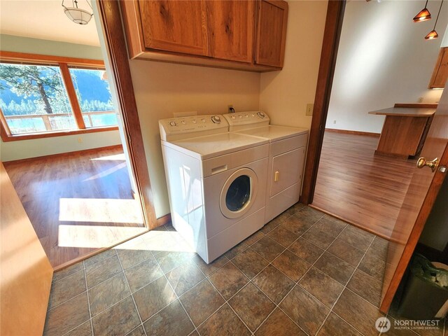 laundry room featuring baseboards, independent washer and dryer, stone finish flooring, and cabinet space