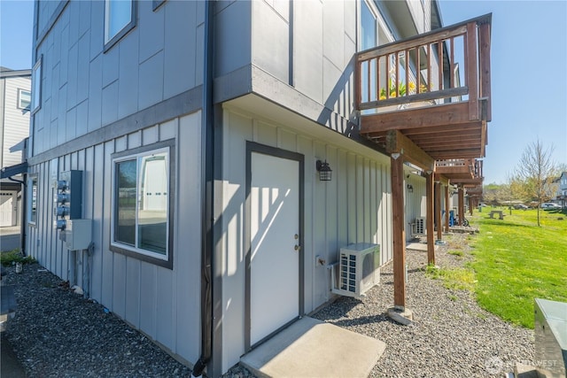 entrance to property with board and batten siding, a wooden deck, and a yard