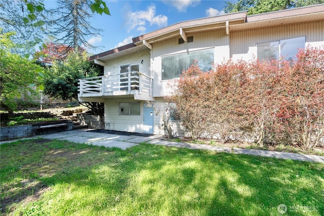 back of house featuring a lawn, a balcony, and a patio area