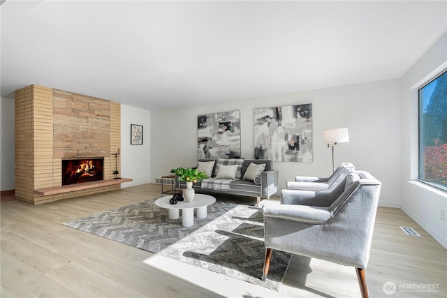 living area featuring baseboards, a fireplace, wood finished floors, and visible vents