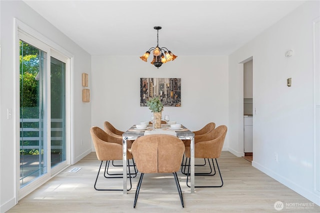 dining space with baseboards, a chandelier, visible vents, and light wood-type flooring