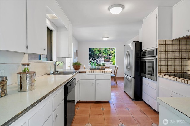 kitchen with a sink, light countertops, white cabinetry, decorative backsplash, and black appliances