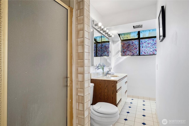 bathroom featuring toilet, baseboards, a shower stall, and vanity