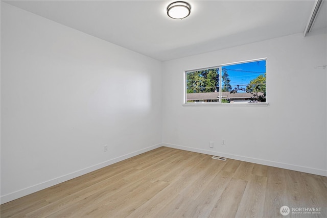 empty room featuring baseboards, visible vents, and wood finished floors