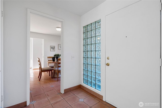 foyer featuring baseboards, light tile patterned flooring, and a wealth of natural light