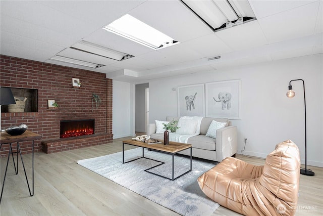 living room featuring baseboards, a fireplace, light wood-type flooring, and visible vents