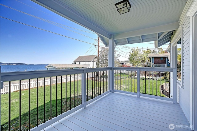 wooden terrace featuring a lawn, a water view, and fence