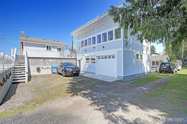 exterior space with dirt driveway, an attached garage, and stairway