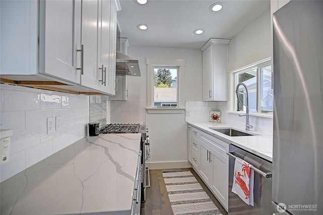 kitchen with a sink, white cabinets, appliances with stainless steel finishes, light stone countertops, and recessed lighting