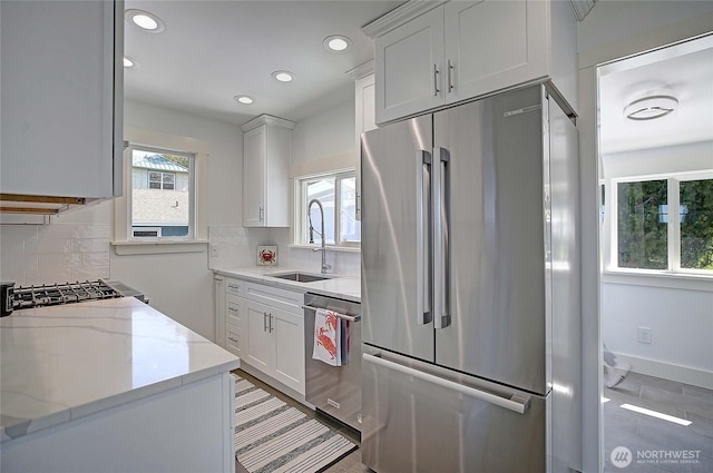 kitchen featuring backsplash, stainless steel appliances, white cabinets, and a sink